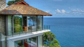 Una casa moderna con balcón de vidrio con vista al mar.