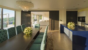 A modern dining area with a long table, green upholstered chairs, and a chandelier. - Villa Samira by Elite Havens (Kamala)