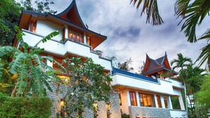 A modern two-story house with a stone facade, multiple balconies, and a well-lit entrance. - Baan Surin Sawan (Choeng Thale)