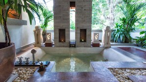 A spa area with a stone fireplace, a central pool, and surrounding plants. - Baan Surin Sawan (Choeng Thale)