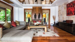 A spacious living area with a wooden ceiling, a sofa, a coffee table, and a statue. - Baan Surin Sawan (Choeng Thale)