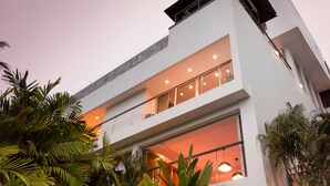 A modern multi-story building with large windows and balconies, surrounded by lush greenery. - Villa Napalai (Choeng Thale)