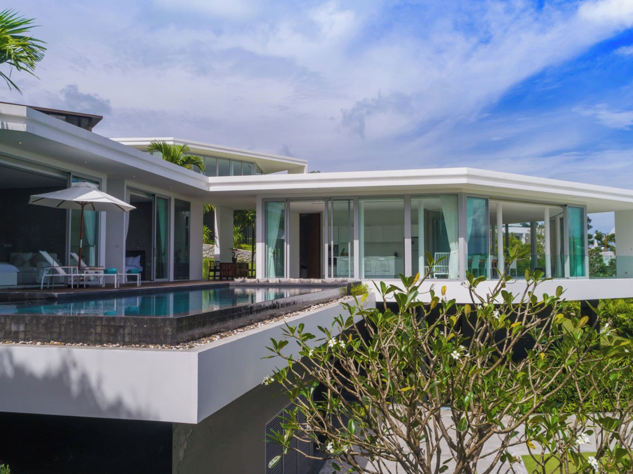 Una casa moderna con piscina, ventanas amplias y mobiliario de exterior.