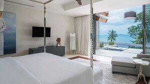 Una habitación de hotel moderna con una cama grande, televisión, escritorio y vista al océano.