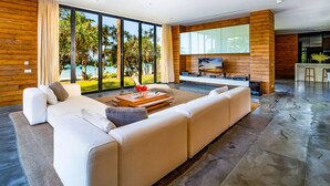 A modern living room with a large sectional sofa, a coffee table, and a TV mounted on a wooden wall.