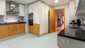 A modern kitchen with wooden cabinets, a built-in microwave, and a stainless steel range hood. - 2-Bedroom Apartment with Rooftop Pool, Village Marina, Olhão (Olhão)