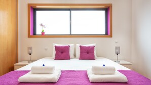 A hotel room with a large bed, two nightstands, a window with a view, and a small potted plant. - 2-Bedroom Apartment with Rooftop Pool, Village Marina, Olhão (Olhão)