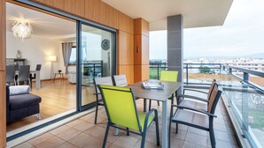 A modern apartment with a balcony, a dining area with chairs, and a view of the cityscape. - 2-Bedroom Apartment with Rooftop Pool, Village Marina, Olhão (Olhão)