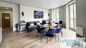 A modern living room with a dining area, a sofa set, and a large window providing natural light. - Urban Flat 60 - Sublime Parisian Flat in Paris (París)