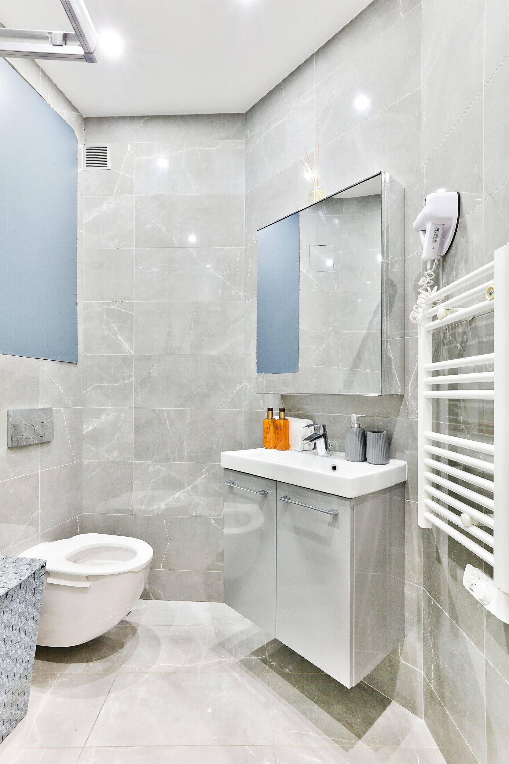 Un baño moderno con inodoro, lavabo, espejo y toallero.