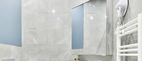 Un baño moderno con inodoro, lavabo, espejo y toallero.