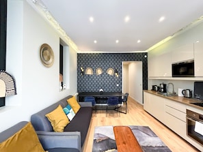 Un espacio habitable compacto con sofá, mesa de comedor y kitchenette.