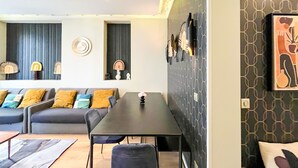 Un soggiorno moderno con un divano, un tavolo da pranzo e sedie. Sono presenti decorazioni a parete e un quadro appeso al muro.