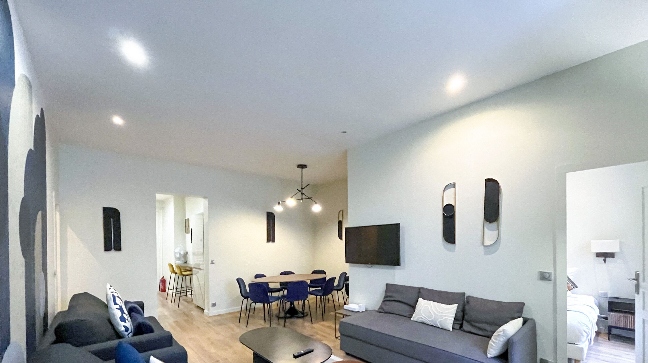 A modern living room with a sofa, a coffee table, and a dining area with chairs and a table.
