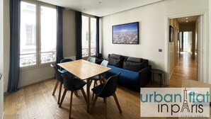 Un soggiorno moderno con un tavolo da pranzo in legno, un divano blu e un dipinto raffigurante un panorama urbano.