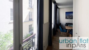 Un appartamento moderno con ampie finestre, un balcone e un'area pranzo con sedie blu.