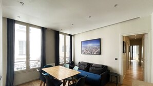 Un salón moderno con una mesa de comedor de madera, un sofá azul y un cuadro con una vista de la ciudad.