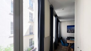 Un apartamento moderno con ventanas amplias, un balcón y un comedor con sillas azules.