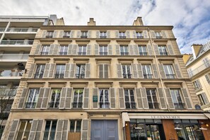 Un edificio de varios pisos con un estilo arquitectónico clásico, que cuenta con una tienda en la planta baja llamada “Le Guynemer”.