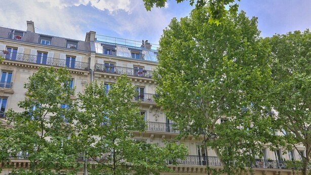 A multi-story building with balconies and large windows.