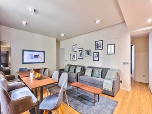A modern living room with a sofa, chairs, a coffee table, and a dining table. - UrbanFlat 79 - Beautiful Large Apartment in Paris Le Marais (París)
