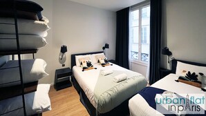 Una habitación de hotel con una cama, una mesita de noche, una ventana con cortinas y una repisa con toallas.