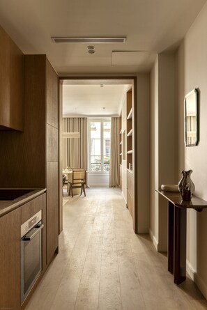 Una cocina moderna con armarios de madera, horno integrado y un pasillo que conduce a un comedor con mesa y sillas.
