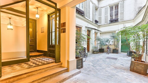 A courtyard with stone flooring, a bicycle, and potted plants.