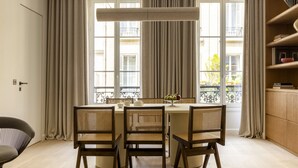 A dining area with a round table, four chairs, and a window with curtains.