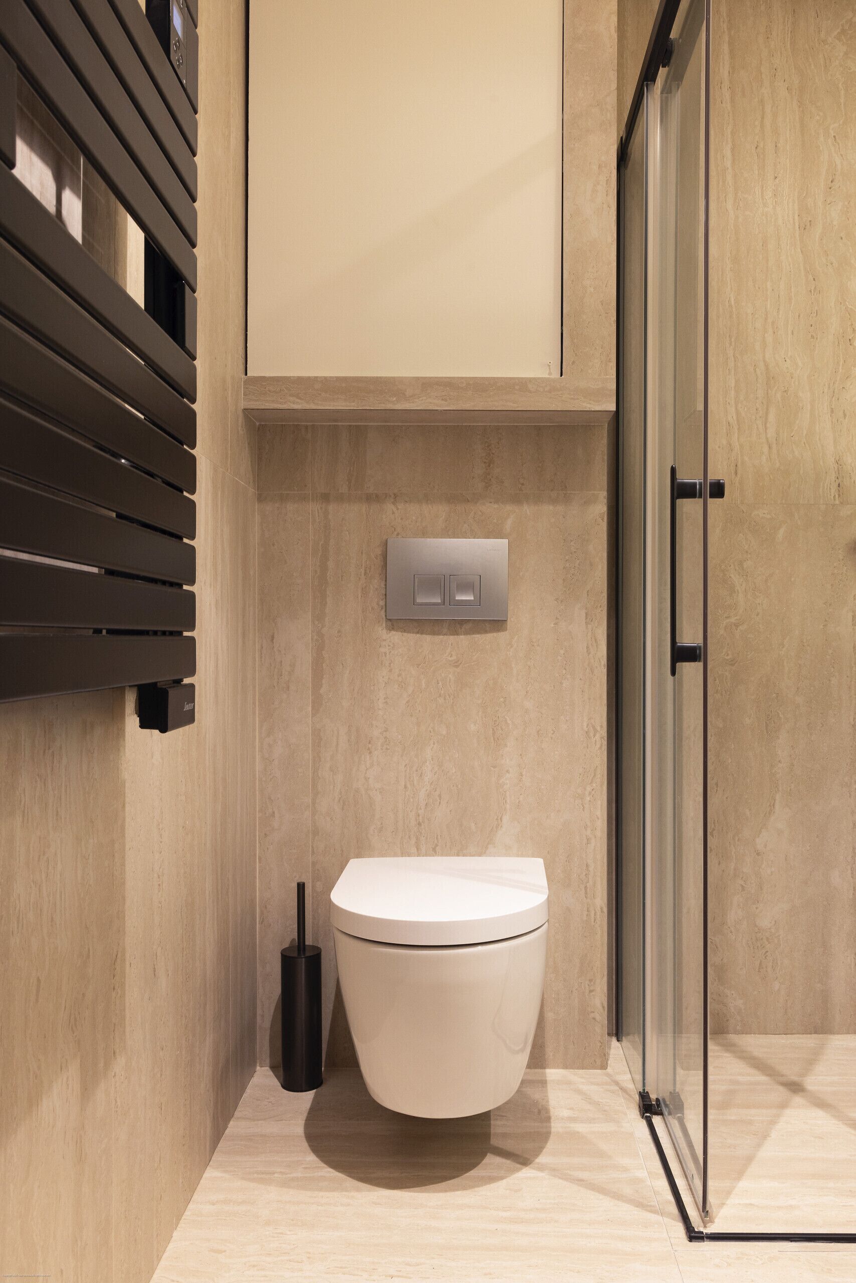 A modern bathroom with a toilet, a flush handle, and a glass shower enclosure.