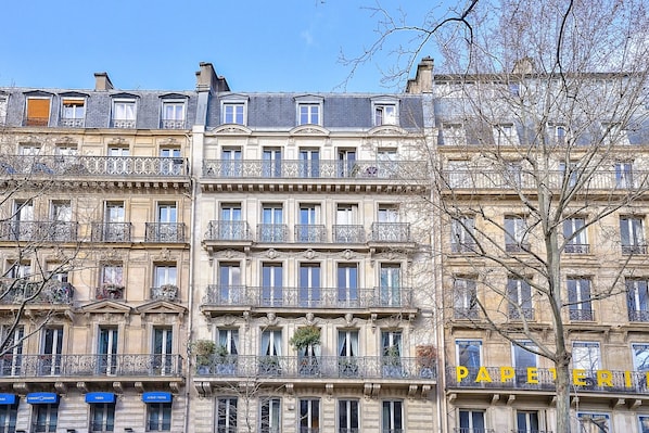 A multi-story building with balconies and a sign reading 'PAPERERIE'.