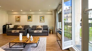 A modern living room with a sofa set, a coffee table, and a large window with a view of buildings. - 102 - Urban Opera Picasso (París)