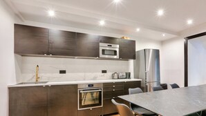 Una cucina moderna con mobili scuri, forno a incasso, microonde e frigorifero in acciaio inossidabile.