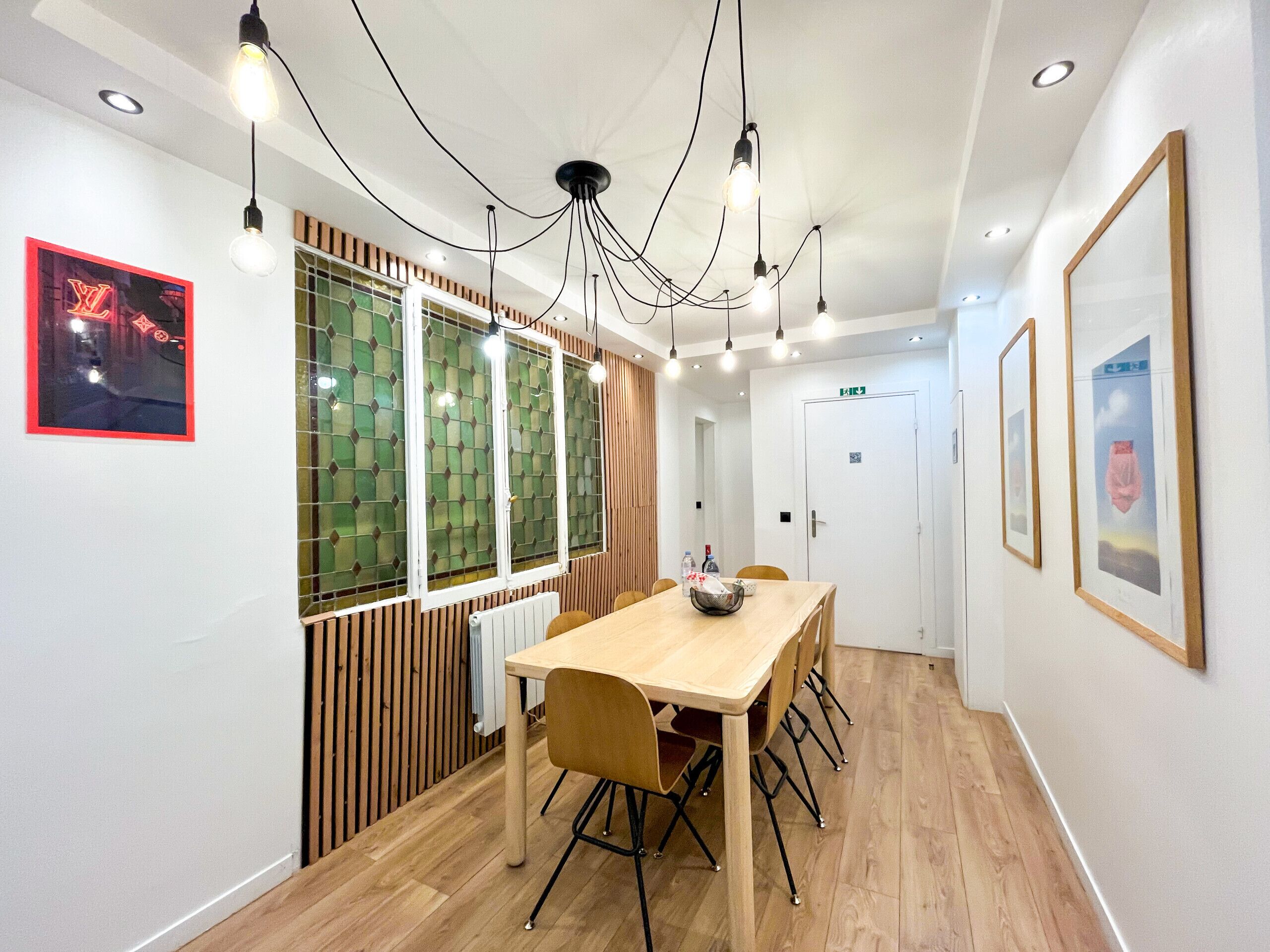 A modern conference room with a wooden table, chairs, and a ceiling light fixture.