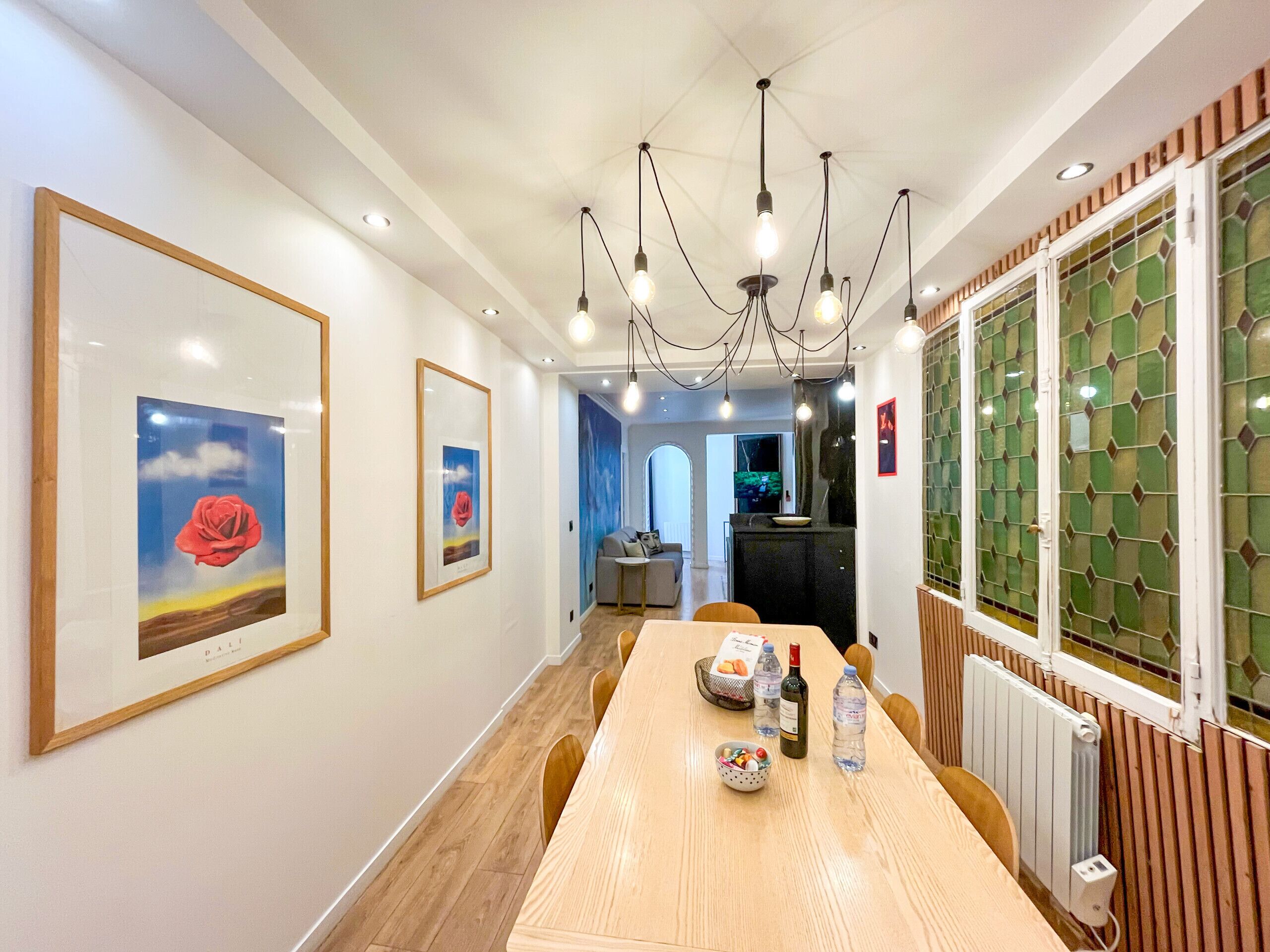 A dining area with a wooden table, framed artwork on the walls, and pendant lighting.