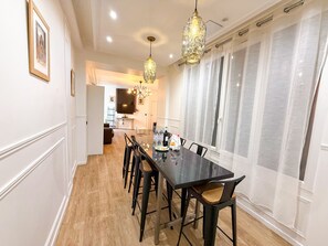 Un comedor con una larga mesa, sillas y candelabros de cristal colgantes.