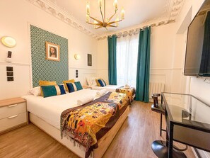 Habitación de hotel con dos camas, un escritorio y un televisor.