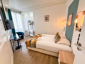 Une chambre d’hôtel équipée d’un lit, d’un bureau, d’une chaise, d’une télévision, d’une armoire et d’une salle de bain.