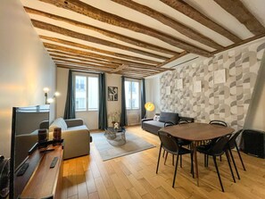 A modern living room with a wooden ceiling, a dining area with a round table, and a sofa.