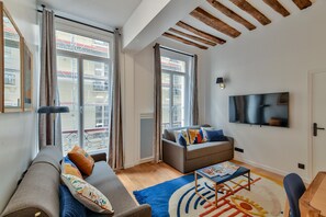 A modern living room with a sofa, a coffee table, and a TV mounted on the wall.