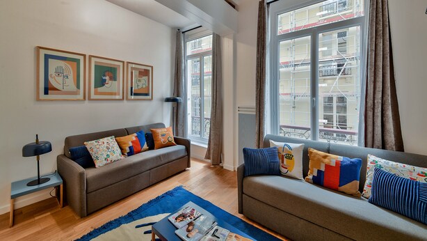 A modern living room with two sofas, a coffee table, and framed artwork on the wall. - 98 - Urban Arts et Métiers (París)