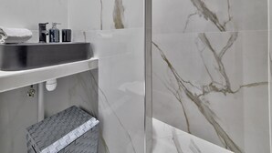 A bathroom with a marble backsplash, a sink with a faucet, and a towel on the counter. - 98 - Urban Arts et Métiers (París)