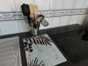 Une cuisine dotée d’un porte-ustensiles contenant des spatules, d’un dosseret carrelé à motifs et d’un plan de travail noir.