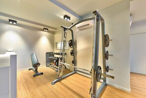 A gym with a squat rack, bench press, and various weights.