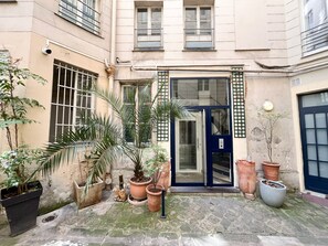 A courtyard with a blue door, potted plants, and a stone floor.
