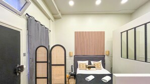 Une chambre d’hôtel de taille réduite, comprenant un lit, une fenêtre et une porte.
