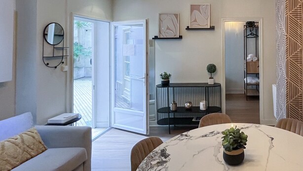 A modern living room with a marble dining table, a sofa, and a chandelier. - Urban Flat 06 - Charming 2 BDR in Paris (París)