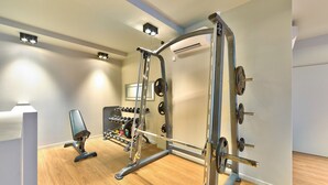 A gym with a squat rack, bench press, and various weights.