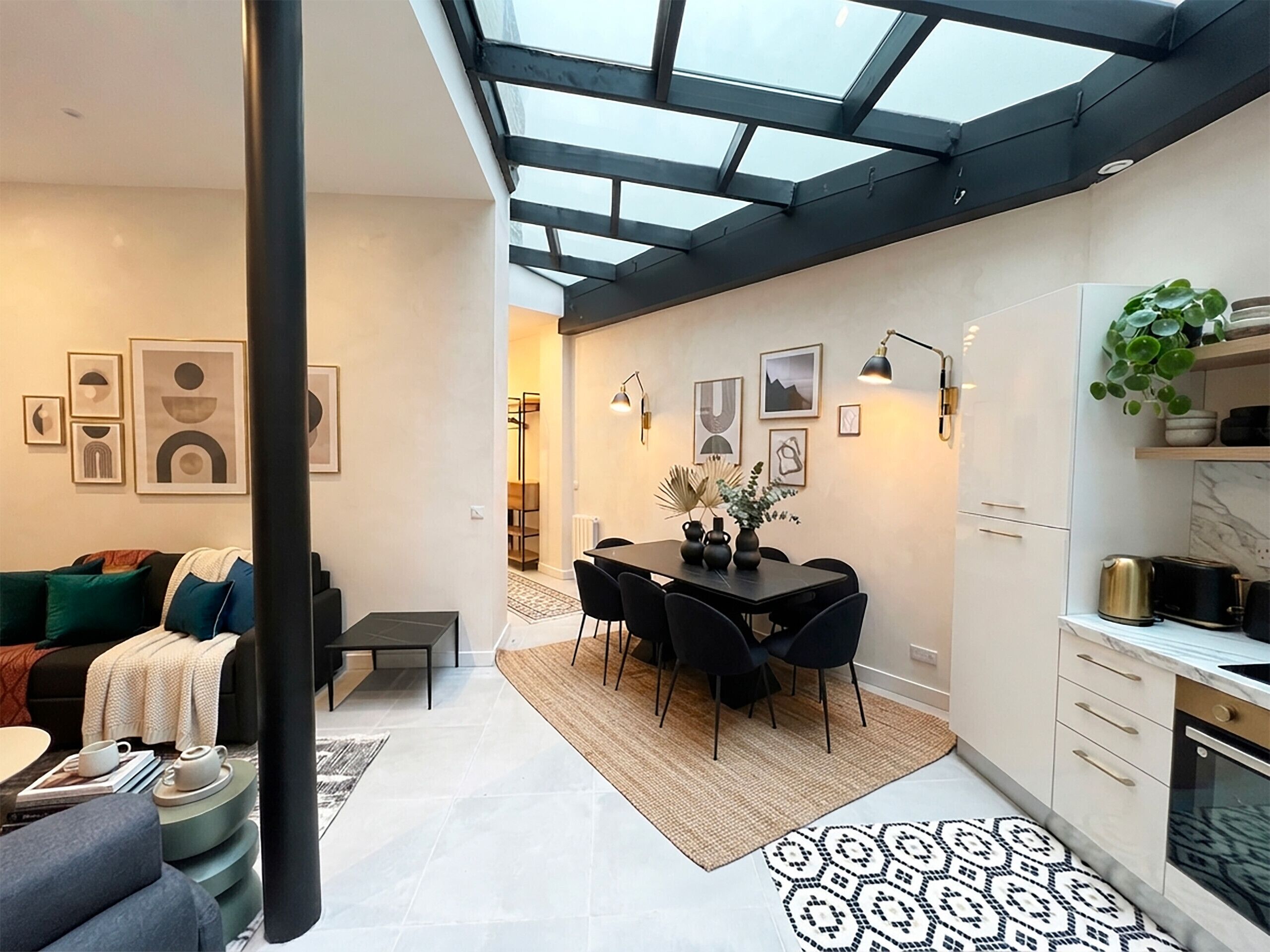 A modern interior with a dining area, kitchen, and a skylight.