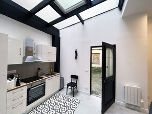 A modern kitchen with white cabinets, a black countertop, and a patterned floor.
